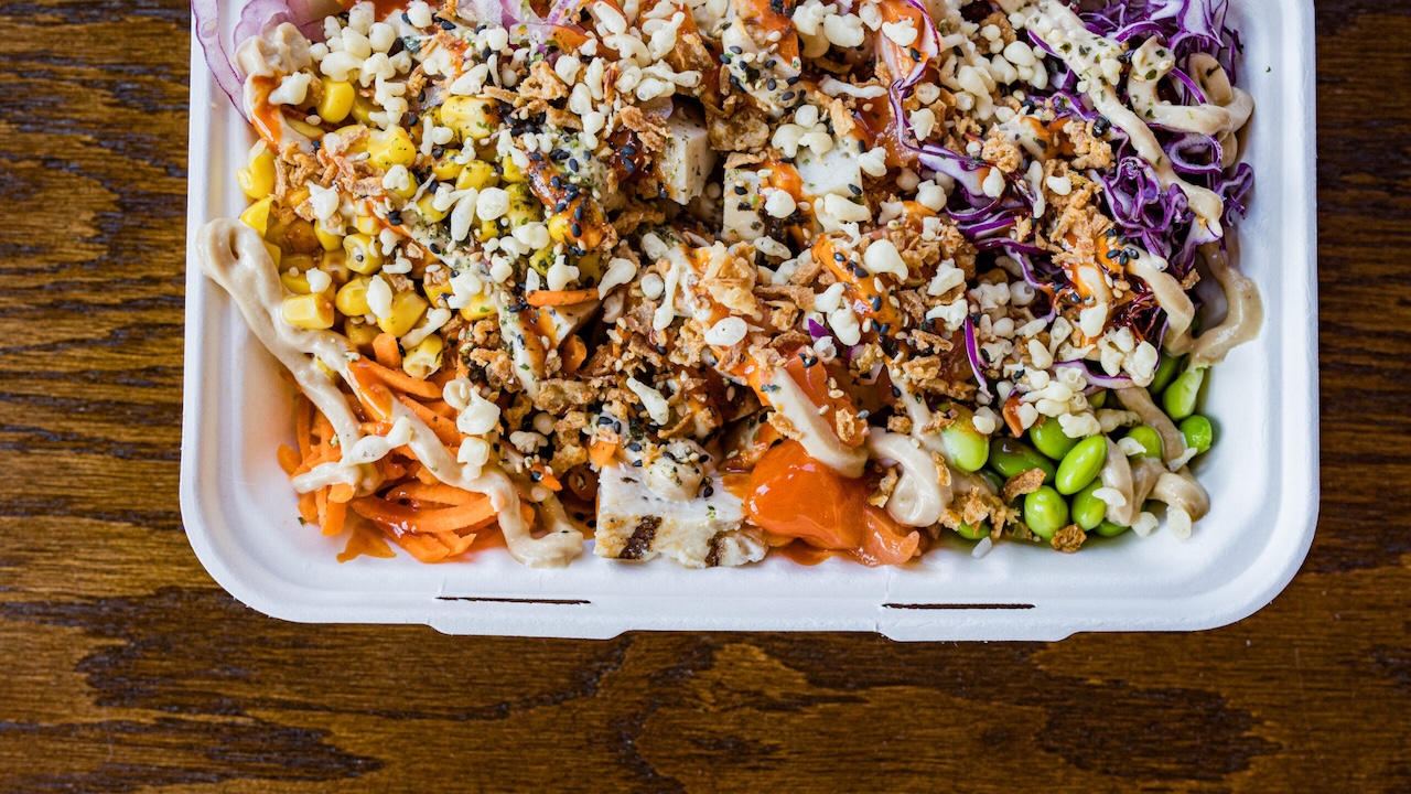 a to-go container full of varying pokebowl toppings