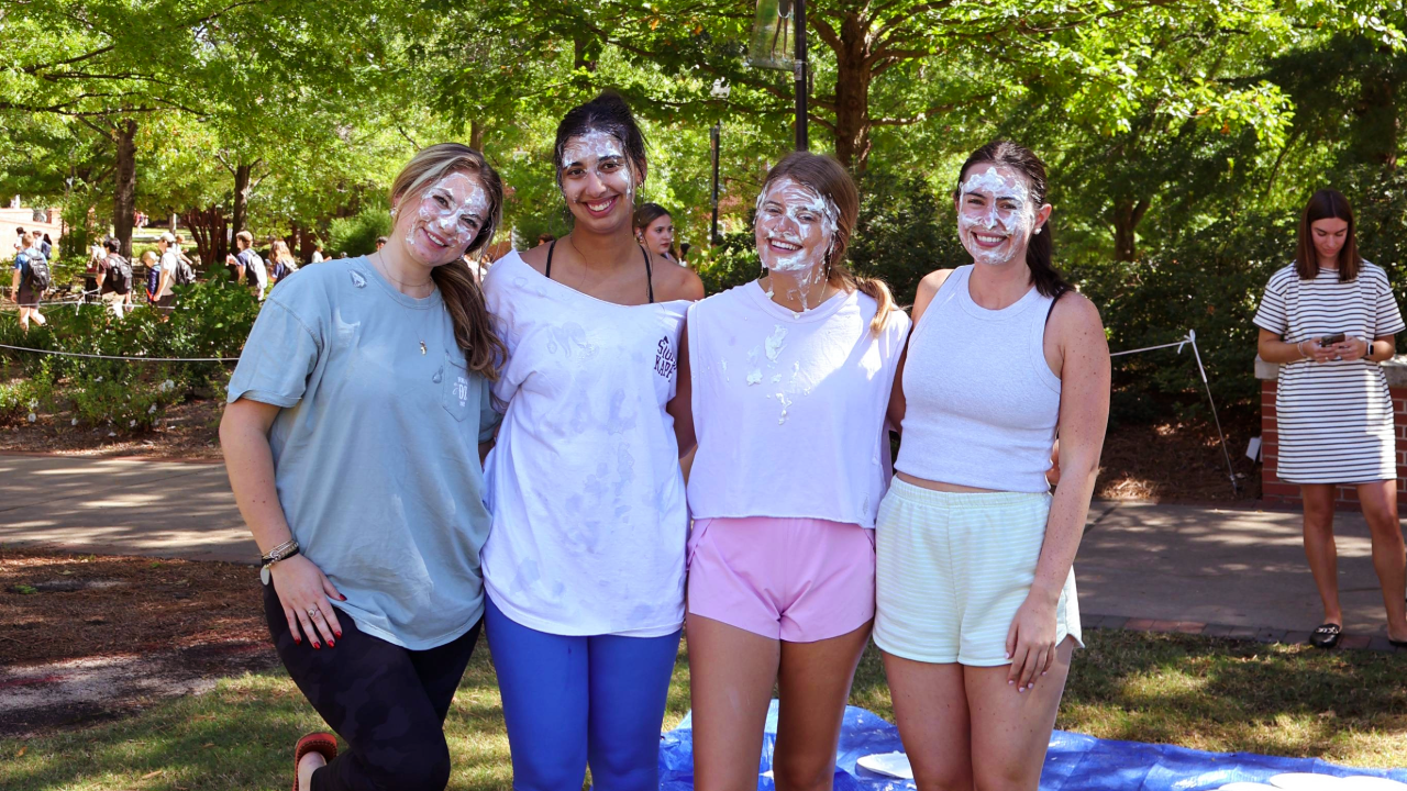 four students smilig at the camera after being pied