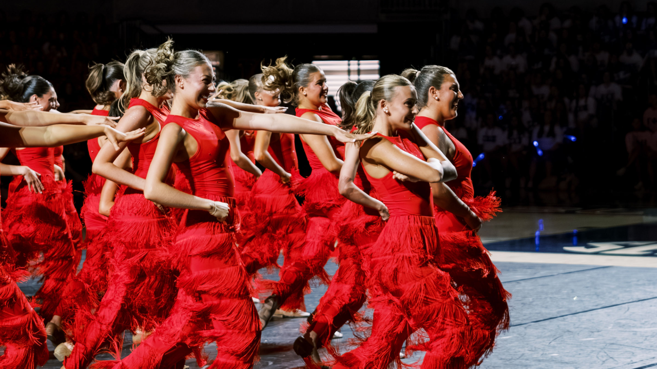 Women of Alpha Chi Omega dancing in fringe pants on stage