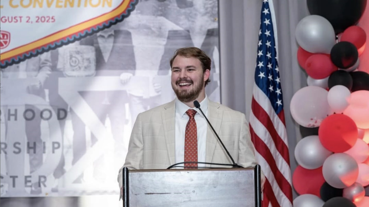 student smiling from podium on stage