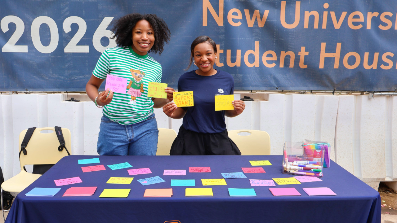two students smiling with colorful paper