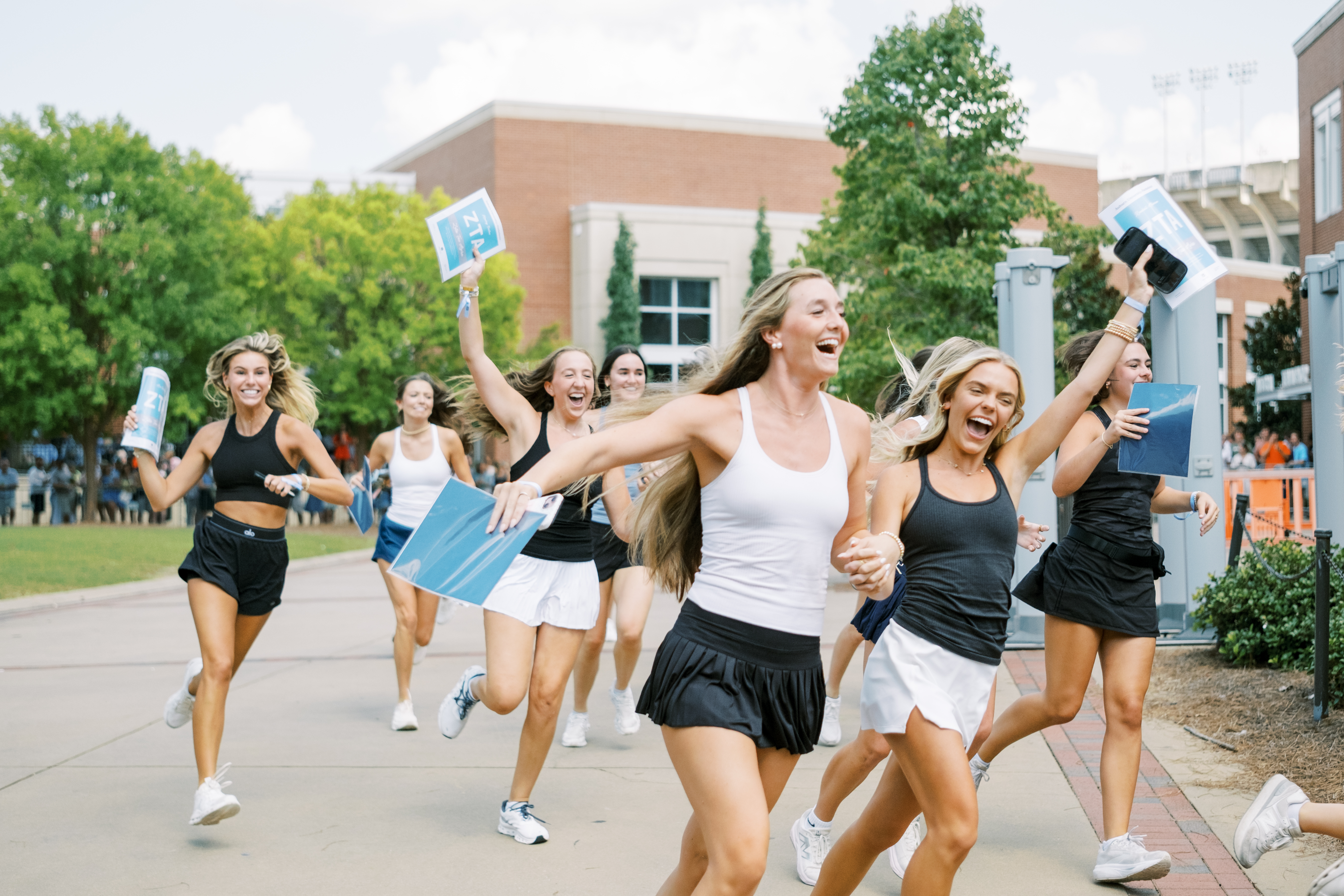 Women with arms raised smiling at the camera while running