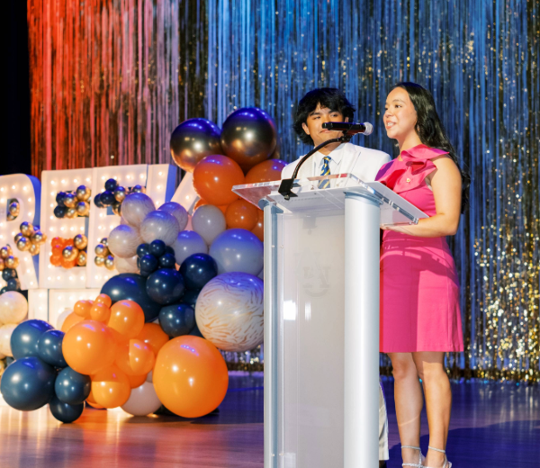 Two hosts speaking at a podium.