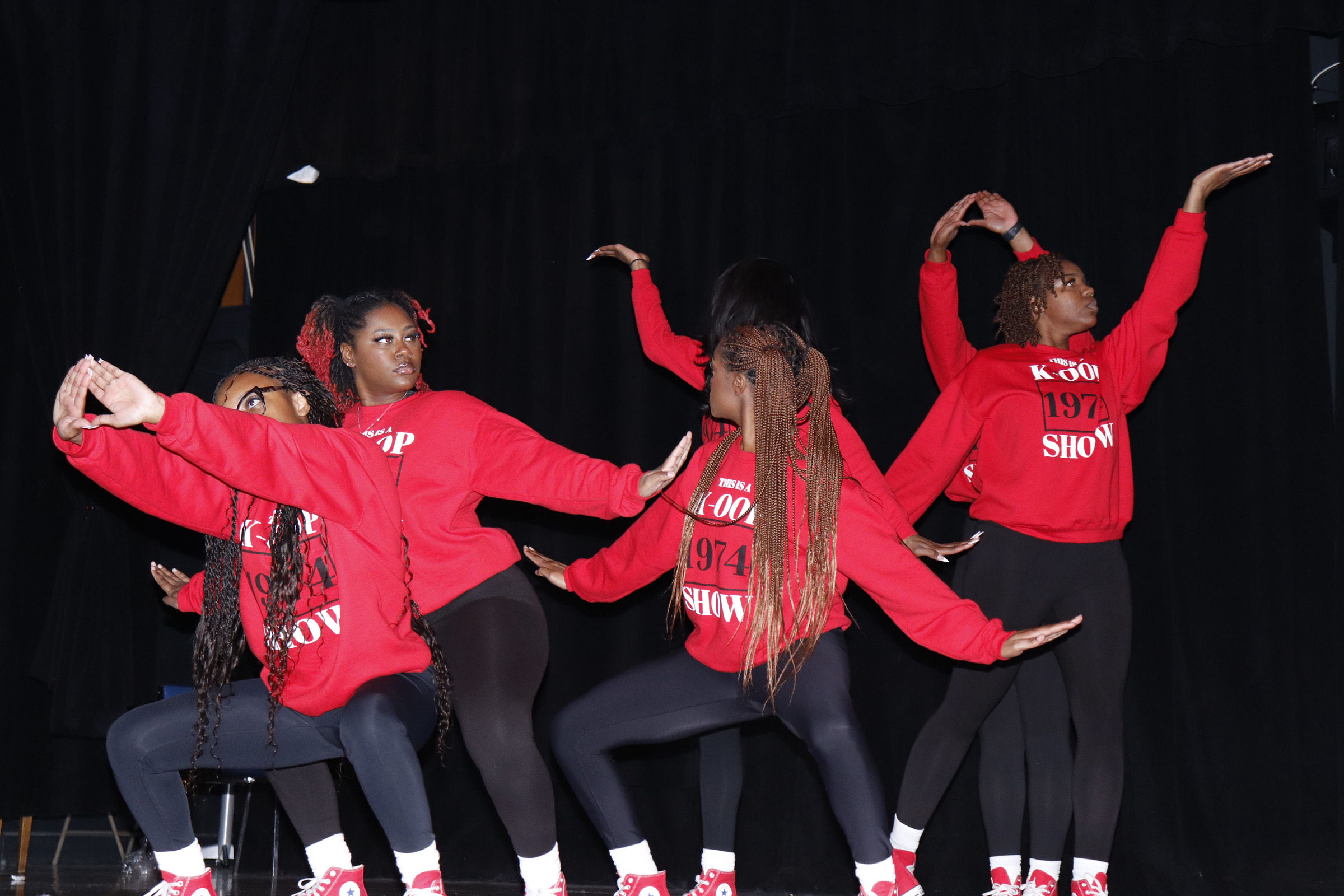 Women in a performance posing on stage.