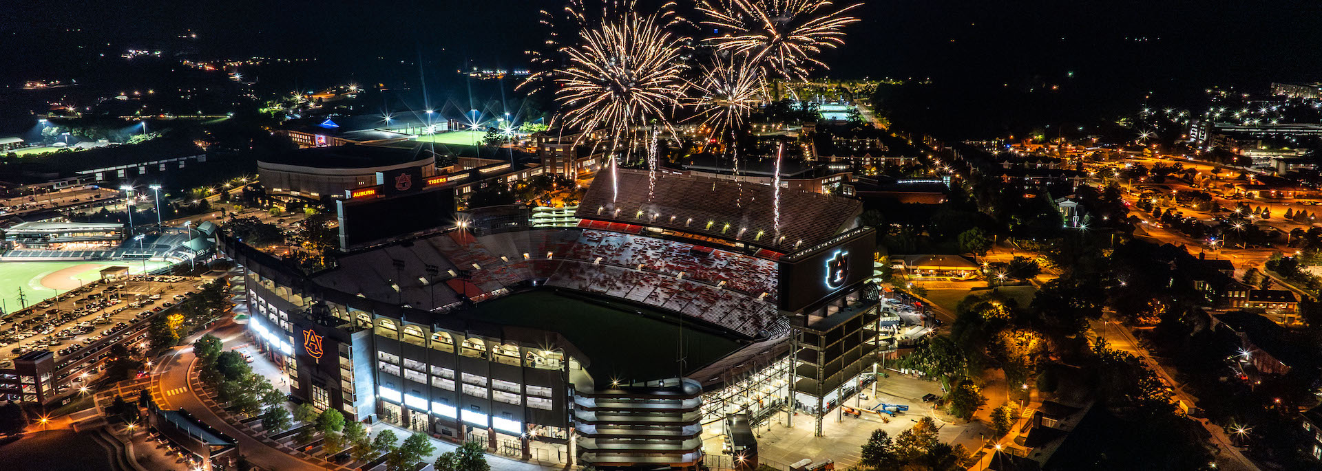 arial shot of Jordan-Hare stadium at night with fireworks exploding above the stadium
