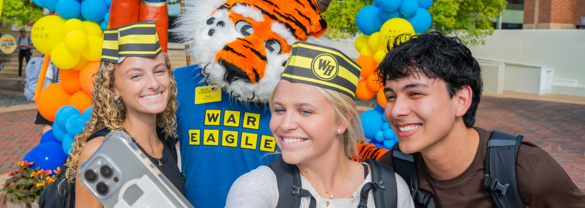 three students taking a selfie with Aubie in front of the Aubie statue at Waffles with Woodard