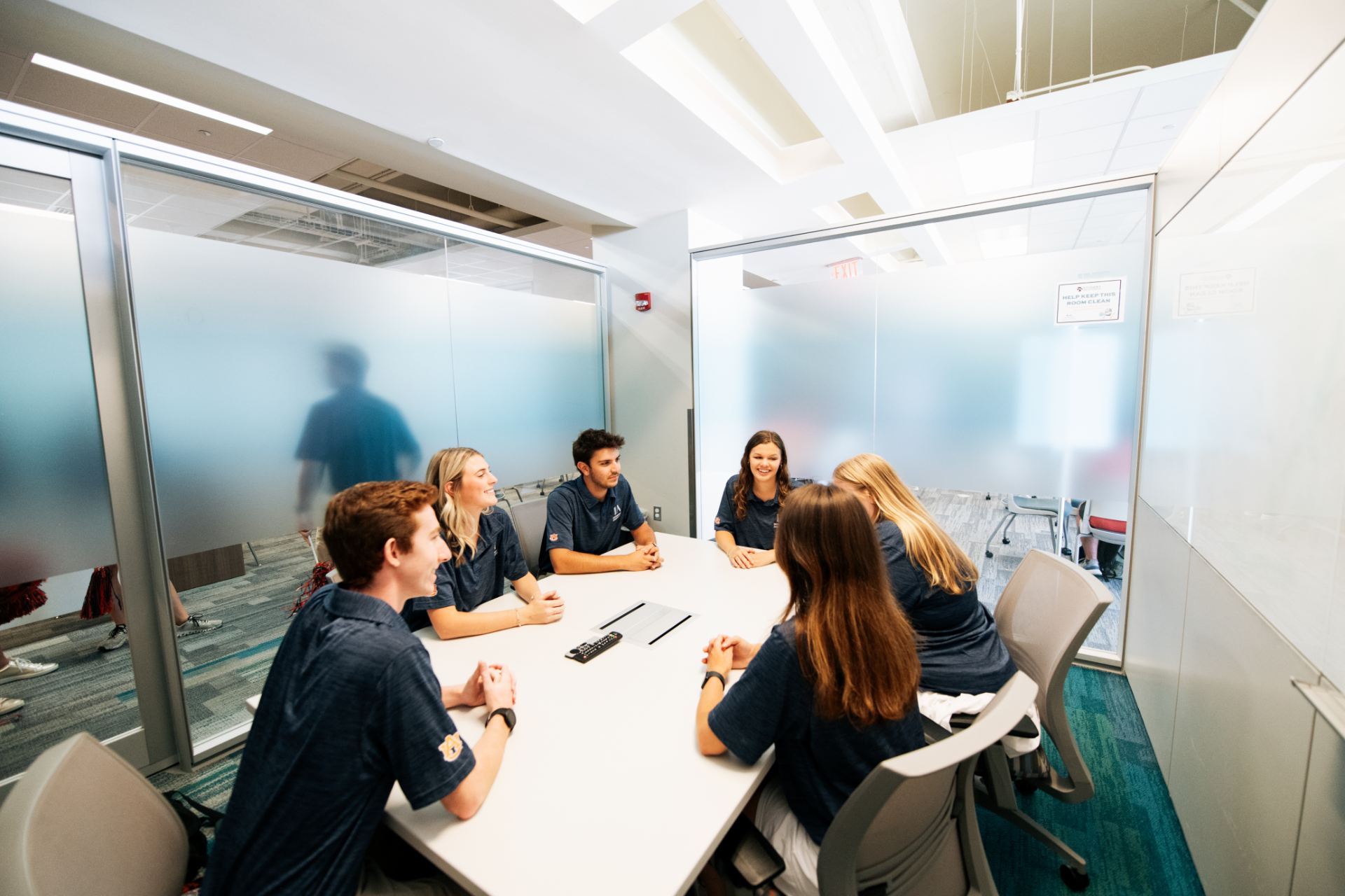 group of students sitting around a table in a room with glass walls
